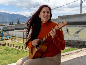 Una mujer con suéter rojo toca una guitarra