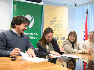 Un hombre y tres mujeres sonríen mientras firman documentos