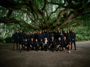 Un gran grupo de personas se reúne, sonriente, bajo un enorme árbol