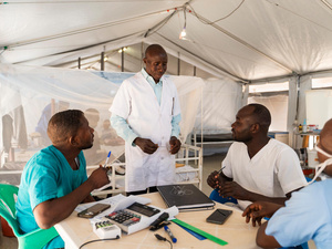 Cuatro médicos sudaneses – todos hombres – conversando alrededor de una mesa circular. Uno de ellos está de pie.