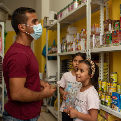 A man and his two daughters look at items at a small grocery store 