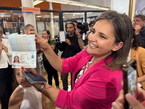 Una mujer muestra su pasaporte sonriendo.