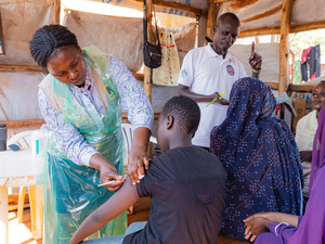Una trabajadora de la salud está vacunando a un chico sudanés