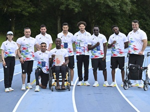 Atletas con uniformes a juego posan para una foto grupal en una pista de atletismo.